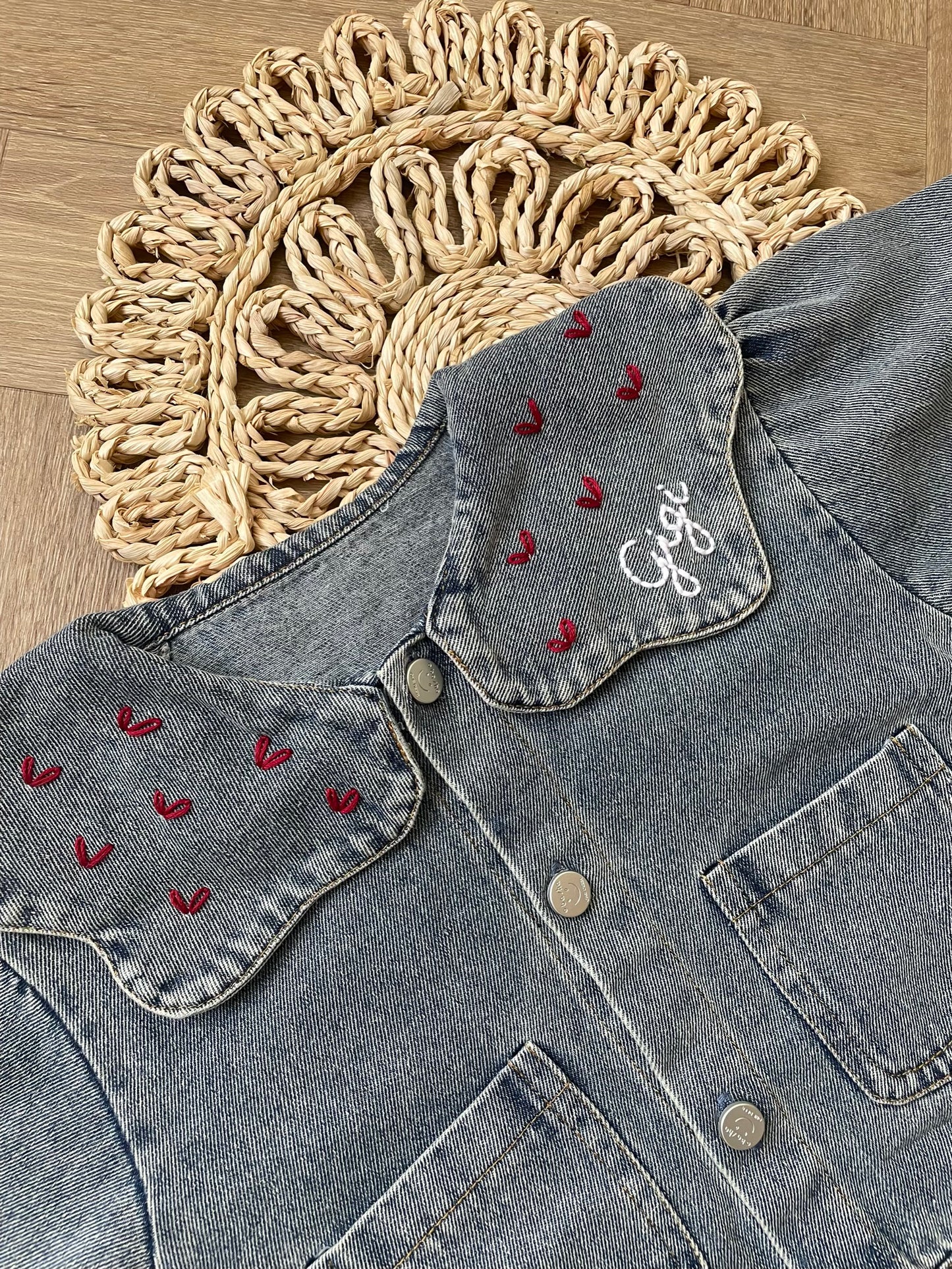 Denim jacket with embroidered designs on a wooden surface