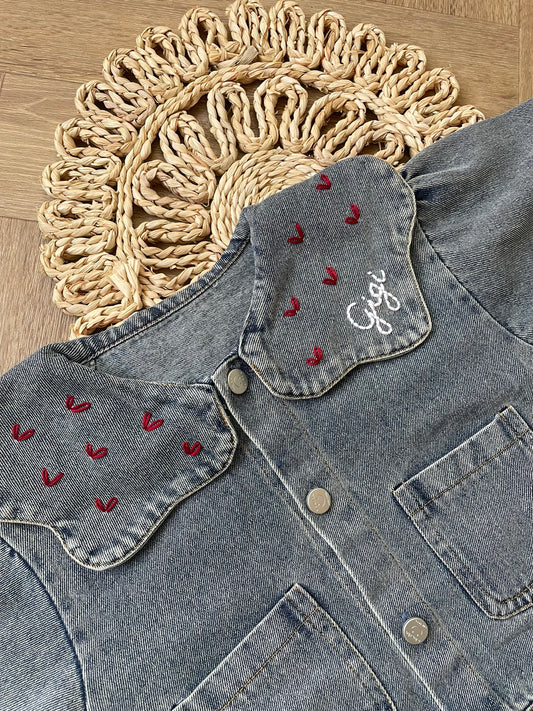 Denim jacket with embroidered designs on a wooden surface